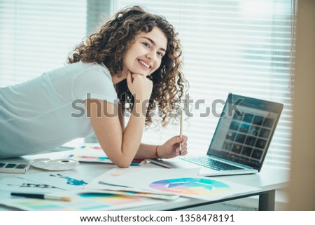 The curly woman working with a brush and a laptop