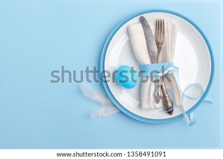 Elegant stylish table setting. Knife and fork on a napkin on a plate on a blue background.