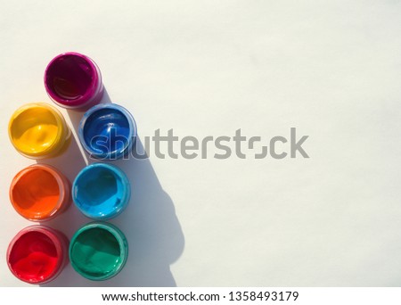 Colored gouache cans on a white background with a shadow, top view