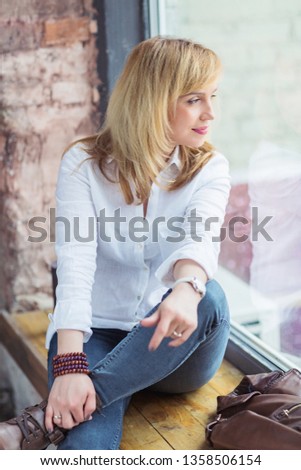 Beautiful mid adult woman smiling, sitting and looking out of the window