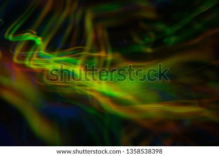 Blurred neon lights in motion. Thin curved multicolor lines on dark background. Lens flare effect.