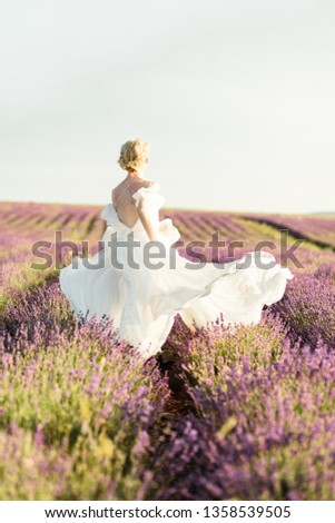 Stuning portrait of girl in light dress in lavender field on golden sunset