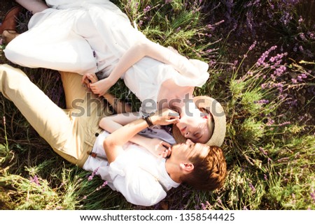 Stunning portrait of the bride and groom lying in a lavender field on sunset