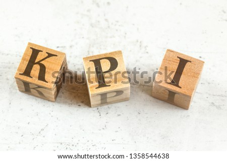 Three wooden cubes with letters KPI (stands for Key performance indicator) on white board.