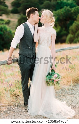 Stunning bride and groom hug each other tender standing on the golden hill near sea