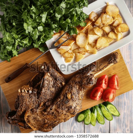Baked leg of lamb with fried potatoes and fresh vegetables. 