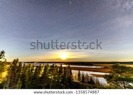 Full moon and stars in clear sky shines over Scandinavian wild forest, lakes, swamps, long exposure night photo, autumn, virgin landscape. Umea river delta, Umea city, Sweden