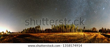 Panorama of very clear deep starry skies with Milky Way above harvested field and wild Scandinavian pine forest, autumn time, Stocksjo village, south of  Umea city, Sweden