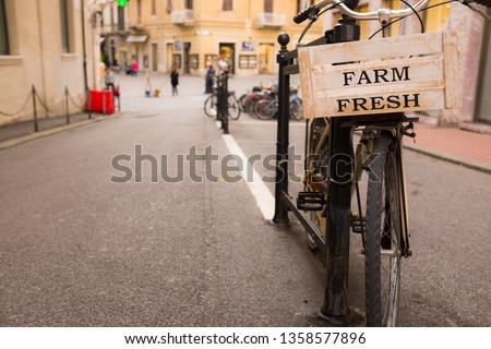 text farm fresh written on a wooden box, on board of a bicycle, with blurred city in the background
