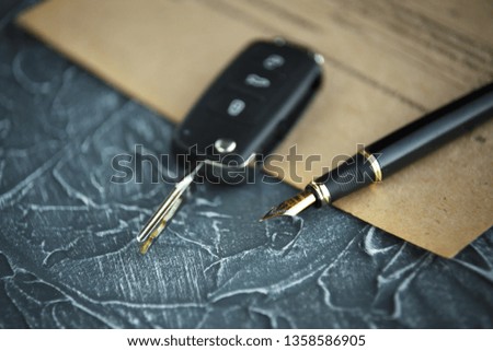 Black car key and money on a signed contract of car sale.
