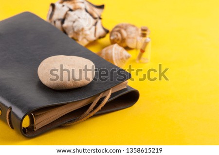 Bright summer holiday background with leather note book, travel and nautical decor on yellow desk