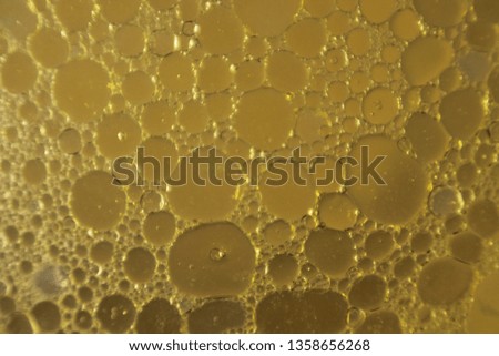 Oily liquid texture with bubbles under microscope.