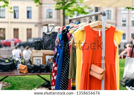 Clothes on the rail on the summer outdoor vintage fashion designer market. Garage sale, reuse the clothes, second hand and eco consumering