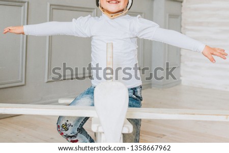 Happy young girl pretending to fly on a wooden plane wearing aviator hat smiling