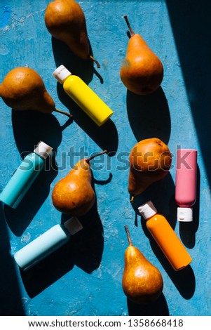 Fruit and colors painting, pear with colored bottle full of pastel painting tint, top view, summer conceptual, hard light with strong shadow