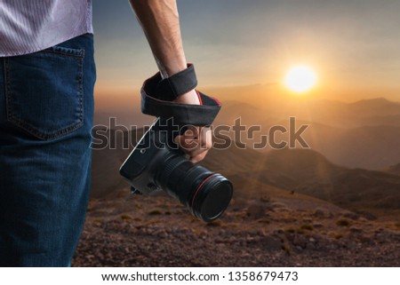Young man holds black modern digital camera