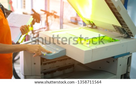 Bussinesswoman using copier machine to copy heap of paperwork in office.Photo select focus.