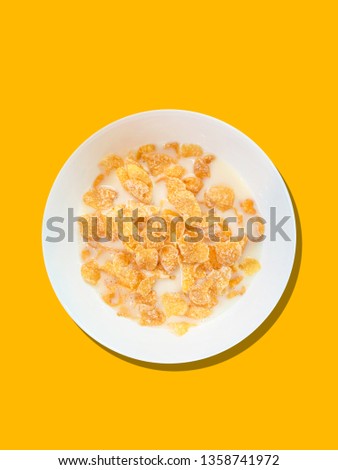 Top view corn flake caramel honey gold with milk in bowl white yellow background 
