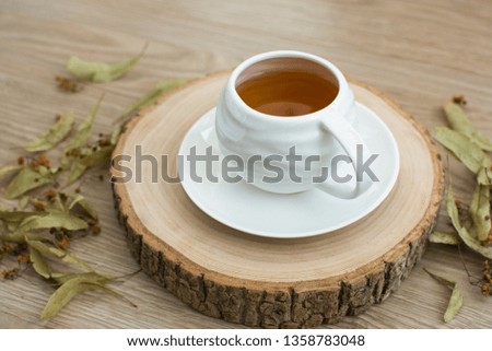 A cup of fresh hot black tea with herbal on a wooden pallet.