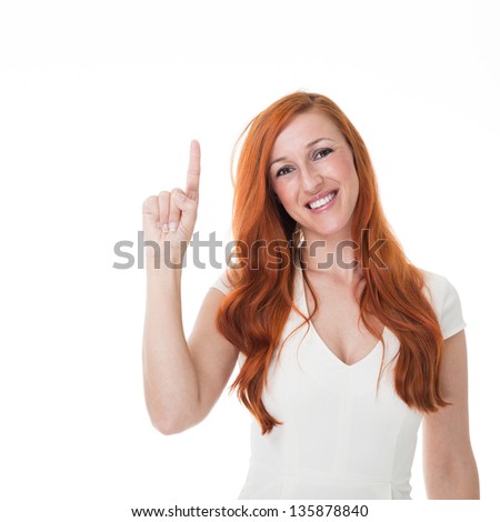 Beautiful redhead woman pointing above her head with her finger towards blank copyspace, isolated on white