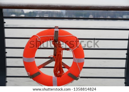 One orange lifebuoy hanging the bar along the river