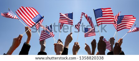 Group of People Waving American Flags over blue sky