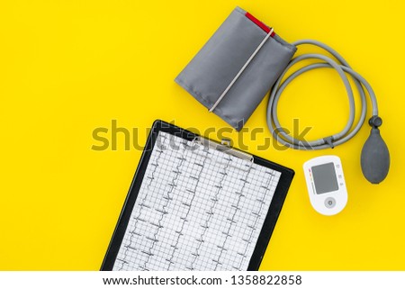 tonometer and cardiogram for heart diseases diagnostic on yellow background top view mockup