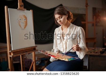 Female painter holds color palette and brush
