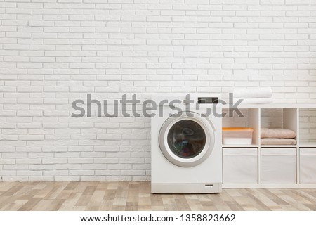 Modern washing machine near brick wall in laundry room interior, space for text Royalty-Free Stock Photo #1358823662