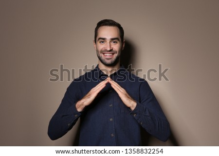 Man showing HOUSE gesture in sign language on color background