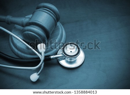 Gavel and stethoscope on table with room for text  Royalty-Free Stock Photo #1358884013