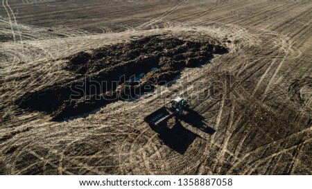 fertilizer on the field. Tractor near the pile of manure. Aerial survey