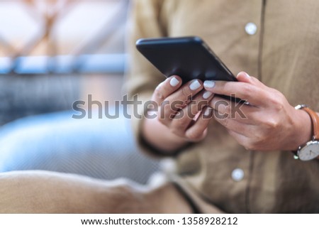 Closeup image of a woman's hands holding and using mobile phone 