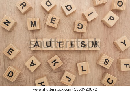 top view of autism lettering made of wooden cubes with different letters on wooden table