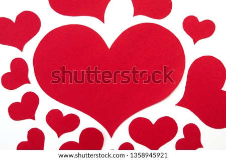 red hearts of different sizes cut from red paper on white background
