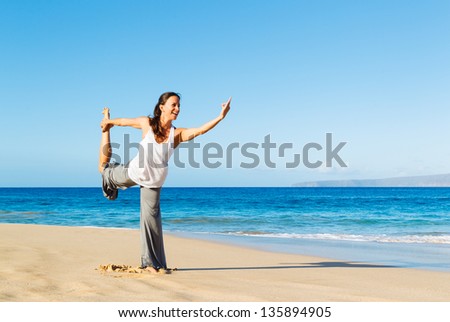 Beautiful young woman stretching during yoga on the beach