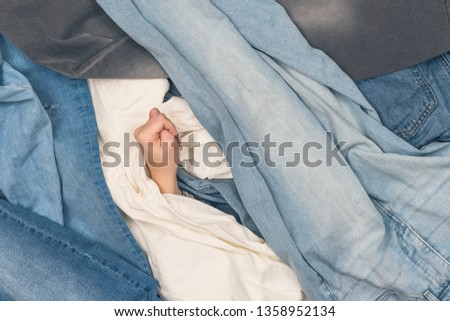Girl hand showing fig sign in the ocean of jeans.  Concept 