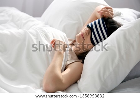 Young woman with sleep mask in bed