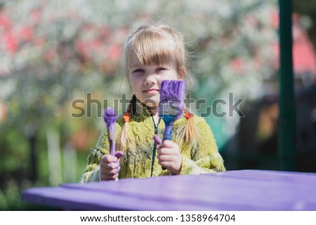Girl with paint brush paint garden furniture