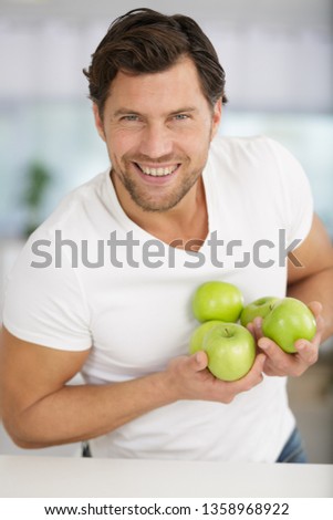picture of man holding green apples