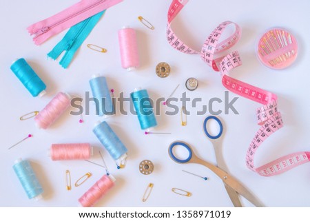 Sewing accessories for needlework in pink and purple and blue tones on white background