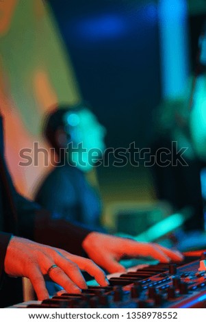 Speech by musicians on stage. Close-up on a musician. Hands and musical instrument closeup. Show in a nightclub, entertainment for adults. Guitar, keys and drum - musical instruments.