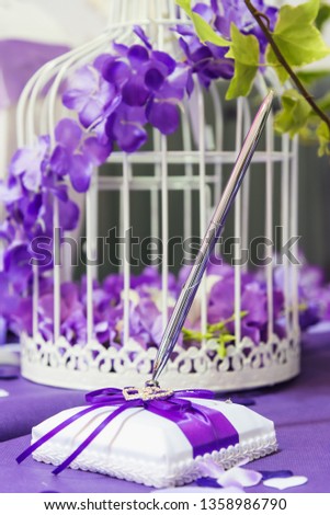 Wedding Book with lilac flowers around a bird cage and a beautiful pen