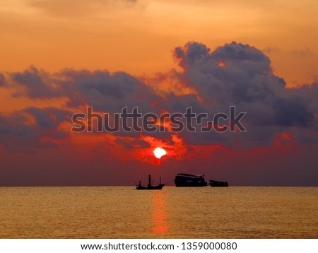 Silhouette picture of the fishing boats are now reaching the coast in the morning. The sky and the Sun in the beautiful