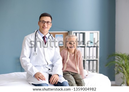 Pediatrician and cute little girl in clinic