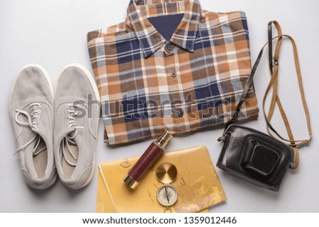Male clothes with travel objects on light background