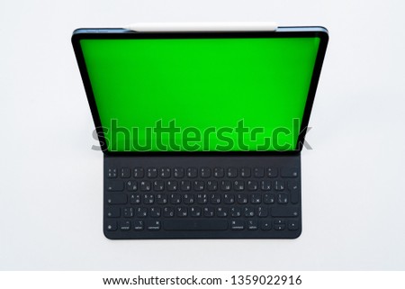 
new tablet on a white background with a keyboard and pen, and green screen