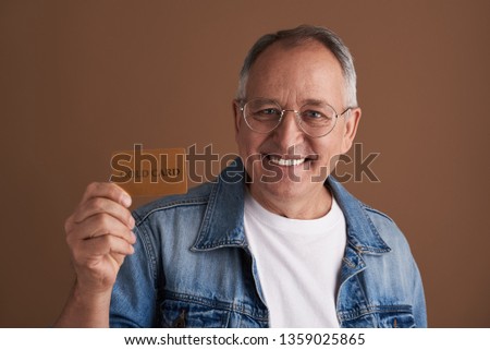Close up photo of the positive adult man wearing glasses and smiling while posing isolated against the brown background