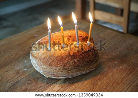 Funny picture of Artisanal sourdough golden baked crusty bread with birthday candles on a wooden board