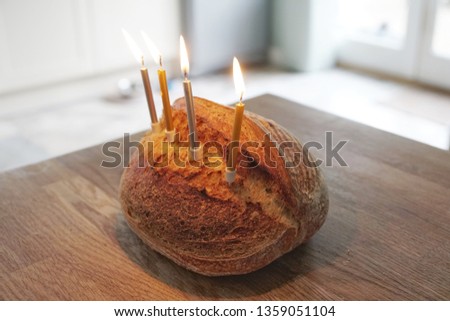 Funny picture of Artisanal sourdough golden baked crusty bread with birthday candles on a wooden board